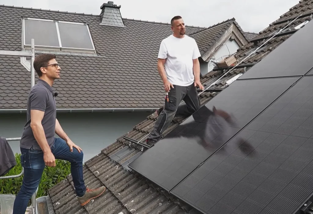 Die Einspeisevergütung soll abgeschafft werden - Unsere Perspektive aus der Praxis 1 Ausschnitt des Tagesschau-Beitrags. Henning Lorang und ein Monteur stehen auf einem Dach neben einer PV-Anlage.